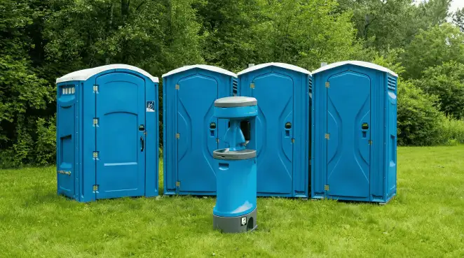 Four blue portable toilets and a matching hand washing station on grass near trees, a common sight at local outdoor events in Albany, NY